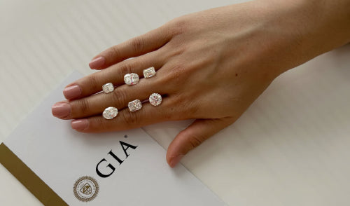 A hand displaying various lab-grown diamond shapes, including oval, emerald, and round cuts, for customisable diamond jewelry