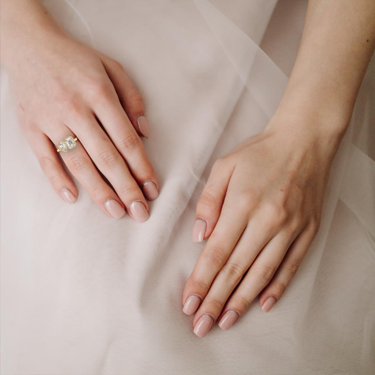 Woman wearing pear and emerald diamond Toi et Moi bezel engagement ring