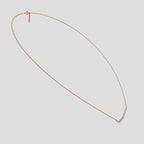 Rose Gold necklace with a curved design and small diamonds on a white background